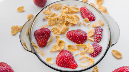 Healthy breakfast strawberry and corn flakes in milk on white background