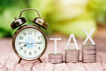Fotobehang TAX text on coins stack and alarm clock for tax concept © jintana