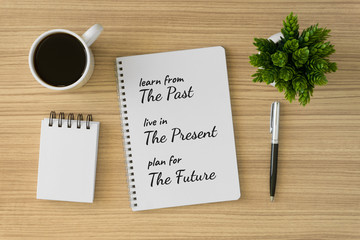 Notebook with motivational and inspirational wisdom quote on wood desk. Learn from the past, live in the present, plan for the future.
