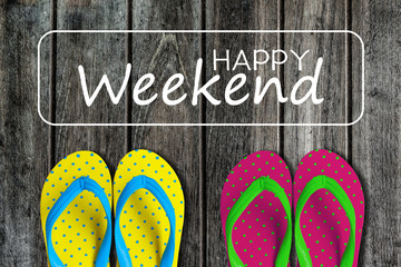 Two pairs sandals with text happy weekend on wooden background