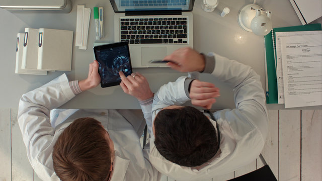 Top view of Doctors discussing images of x-ray scan on tablet