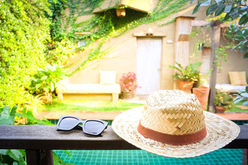 Sunglasses with vintage straw hat fasion on wooden table, Blur background for vintage resort hotel, Concept Summer