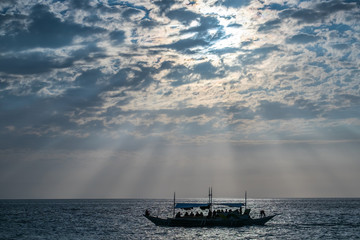 Silhouette of a boat with people sailing at amazing sunset over the sea at Boracay island Philippines