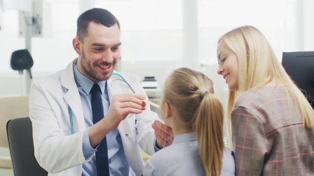 Friendly Doctor Checks up Little Girl's Sore Throat, Mother is Present for Support. Modern Medical Health Care, Friendly Pediatrician and Bright Office. Shot on RED EPIC-W 8K Helium Cinema Camera.