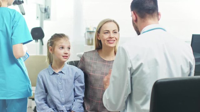 Mother with Sweet Little Girl Visit Friendly Pediatrician. Doctor Talks to Them after Thorough Examination. Brightand Modern Medical Office. Shot on RED EPIC-W 8K Helium Cinema Camera.