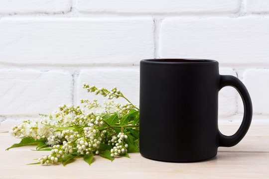 Black coffee mug mockup with white spiraea flowers