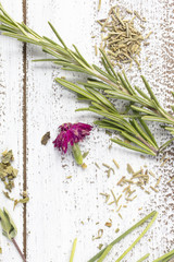 Fresh and dry Rosemary herbs on a rustic table top with edible flowers