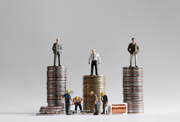 The concept of income gap. The stack of coins with miniature people.