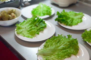 Green lettuce leaves on the plates on the kitchen table background.