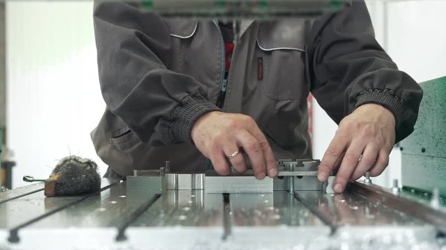 Worker with a scraper chamfering removing burrs on metal object for manufacturing industrial CNC machines