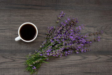 The cup of coffee and lavender flowers on the wooden background
