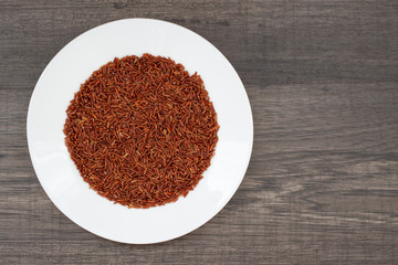 Brown rice on a white plate on a wooden table. Healthy diet food