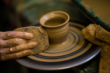 Sculpts in clay pot closeup. Modeling clay close-up. Caucasian man making vessel daytime of white clay in fast moving circle. Art, creativity. Ukraine, cultural traditions. Hobbies
