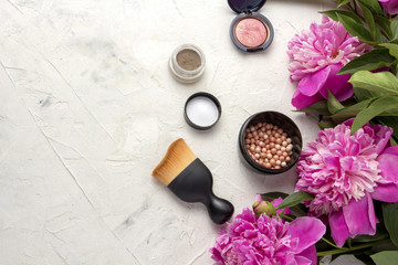 Decorative cosmetics. Pink peonies on a light background. Top view.