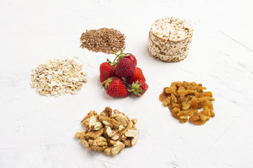 Natural sources of minerals. Oat flakes, flaxseeds, strawberries, rice loaves, walnuts and raisins. Concept of healthy eating.