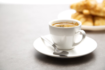 Cup of fresh coffee with croissants on dark background