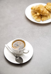 Cup of fresh coffee with croissants on dark background