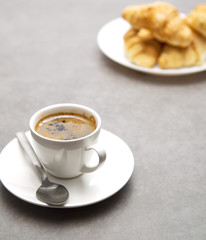 Cup of fresh coffee with croissants on dark background