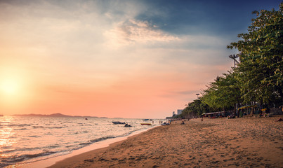 Beach with palm trees at sunset. Jomtien beach in Thailand.