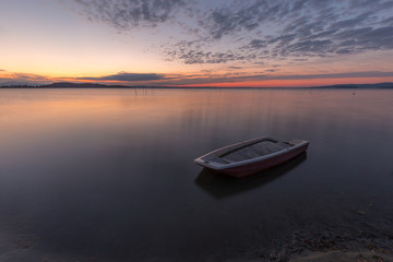 Fototapeta na wymiar A little fishing boat in the middle of perfectly still water at 