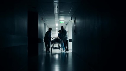 Emergency Department: Doctors, Nurses and Surgeons Push Gurney / Stretcher with Seriously Injured Patient towards the Operating Room. Shot on RED EPIC-W 8K Helium Cinema Camera.
