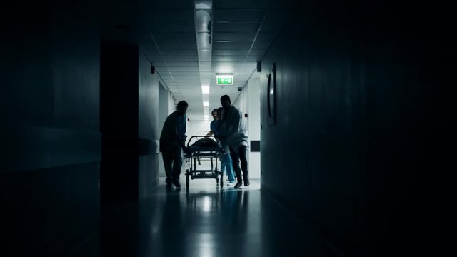 Emergency Department: Doctors, Nurses and Surgeons Push Gurney / Stretcher with Seriously Injured Patient towards the Operating Room. Shot on RED EPIC-W 8K Helium Cinema Camera.