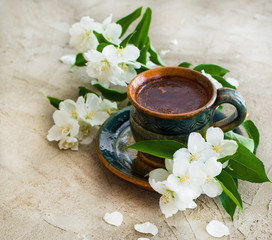 Obraz na płótnie Canvas a cup of coffee on gray background, good morning coffee with white jasmine flowers 