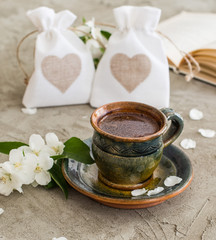Obraz na płótnie Canvas a cup of coffee on gray background, good morning coffee with white jasmine flowers , and two presents with hearts