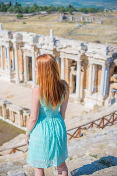 Girl tourist taking picture of Hierapolis in Turkey, Pamukkale, beautiful landscape with ruin, trees and mountain, woman in lace summer dress  