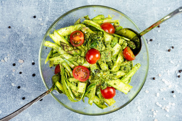 salad with asparagus, cherry tomatoes and parsley on the cristal bowl, grey background
