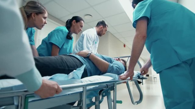 Emergency Department: Doctors, Nurses and Paramedics Run and Push Gurney / Stretcher with Seriously Injured Patient towards the Operating Room. Shot on 4K UHD Camera.