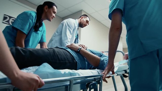 Emergency Department: Doctors, Nurses and Paramedics Run and Push Gurney / Stretcher with Seriously Injured Patient towards the Operating Room. Shot on 4K UHD Camera.