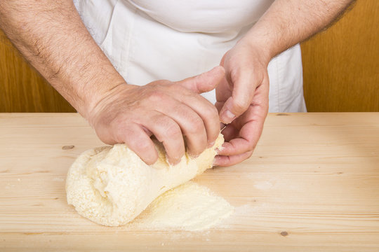 Cocinero amasando a mano una masa de harina para cocinar pasta o pan