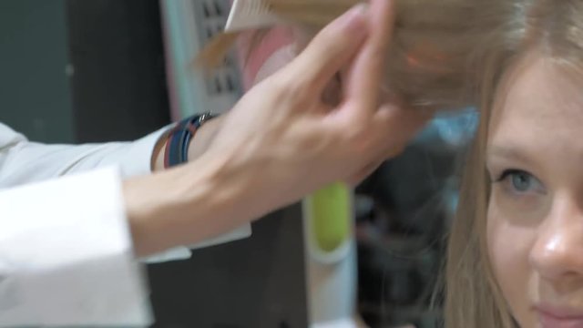 Close-up of barber cuts young woman hair