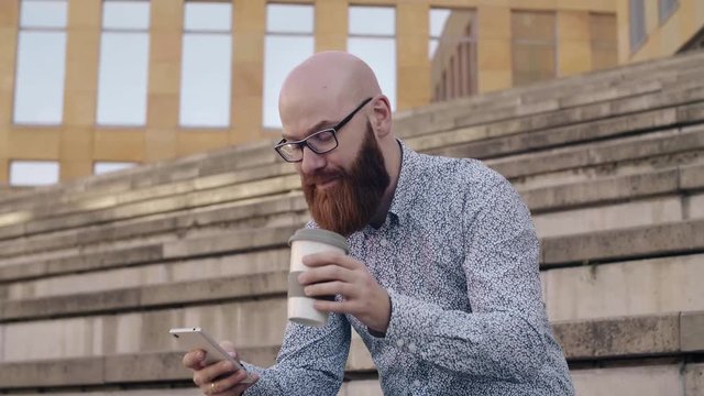 Man drinking coffee and using mobile phone outdoors