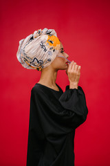 Portrait of a fashionable Muslim woman model in a head scarf hijab against a red background in a...