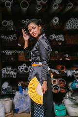 Fototapeta na wymiar Fashion portrait of a young, attractive and elegant Muslim Malay Asian woman wearing traditional but trendy clothing in an industrial workshop. 