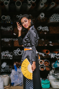 Fashion portrait of a young, attractive and elegant Muslim Malay Asian woman  wearing traditional but trendy clothing in an industrial workshop. 