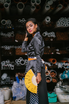 Fashion portrait of a young, attractive and elegant Muslim Malay Asian woman  wearing traditional but trendy clothing in an industrial workshop. 