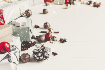 wrapped present boxes with ornaments pine cones anise and lights on white wooden background top view, space for text. merry christmas concept. seasonal greetings card. happy holidays