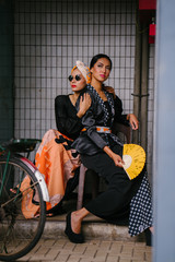 Naklejka premium Portrait of two young, attractive and beautiful Muslim Malay women on a street in Asia during the day. They are dressed up to go visiting for Raya and look fashionable and beautiful. 