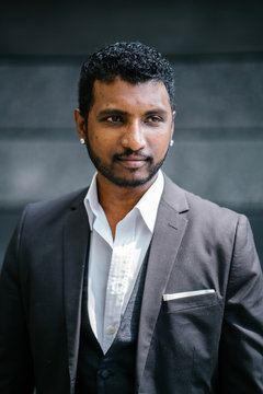 Professional portrait head shot of a handsome young Indian man in a 3 piece suit during the day. 