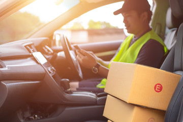 The dispatcher uses the delivery program using a mobile phone. In the van with parcels on the outside of the warehouse.
