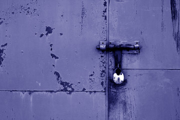 Old padlock on metal gate in blue color.