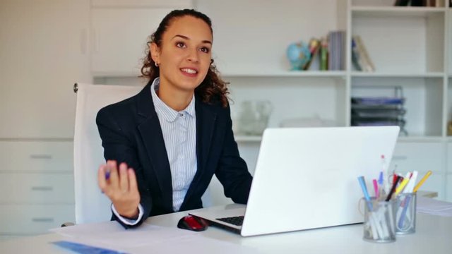 Smiling young woman working with paperwork and laptop in office