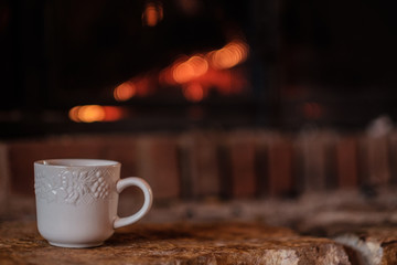 A white coffee mug on the hearth of a warm brick fireplace