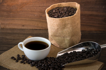 still life photo of hot coffee and coffee beans on the wood table 