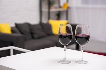 close-up shot of red wine on table in front of blurred living room on background