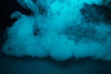 Colored turquoise smoke on a black background closeup