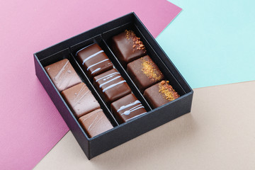 Assortment of luxury bonbons in box on colorful purple and blue background